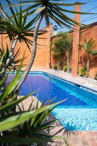 a swimming pool in front of a building with palm trees at La Huerta golf & hotel in Cholula