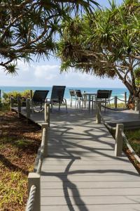 a wooden walkway with chairs and tables on the beach at Nautilus Beach Resort by Charlesworth in Coffs Harbour