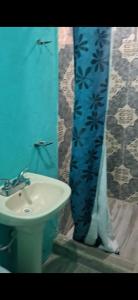 a bathroom with a sink and a blue shower curtain at Finca EL CHACHALACO in Agua Buena +10 photos
