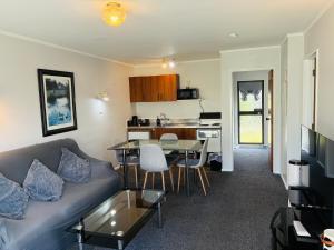 a living room and kitchen with a couch and a table at Awatea Park Motel in Palmerston North