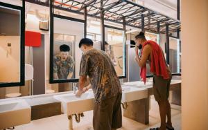 two men standing in front of sinks in a bathroom at Lub d Siem Reap - Near Pub Street & Angkor Wat in Siem Reap