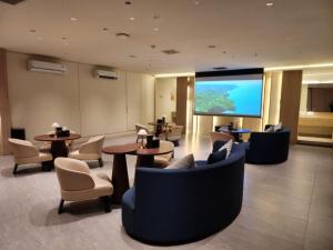 a hotel lobby with tables and chairs and a large screen at Ow! Hotel Boutique Kemayoran in Jakarta