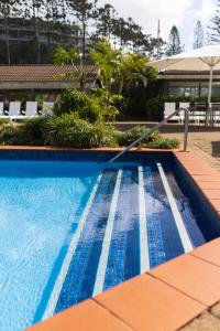 a swimming pool with a hose in front of a building at Nautilus Beach Resort by Charlesworth in Coffs Harbour +47 photos