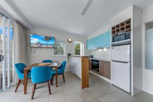 a kitchen with a dining table and blue chairs at Ocean Rise at Airlie Two in Airlie Beach