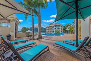 a deck with chairs and umbrellas at a resort at Ocean Rise at Airlie Two in Airlie Beach
