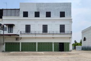 a large white building with green garage doors at Adi Inn Homestay RedPartner in Sunggal