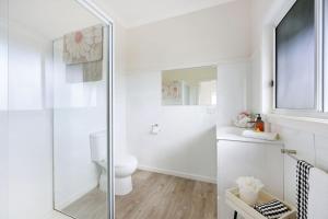 a white bathroom with a toilet and a glass shower at Jimley Cottage in Warrnambool +19 photos