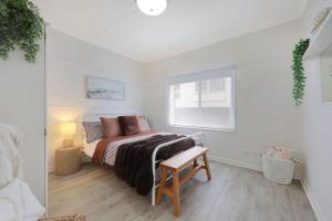 a white bedroom with a bed and a window at Jimley Cottage in Warrnambool