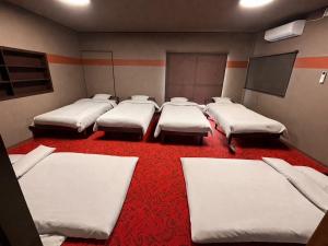 a room with four mattresses lined up on a red carpet at Lento Stay HAGI in Hagi