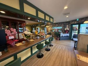a bar in a restaurant with green chairs and flowers at Lento Stay HAGI in Hagi