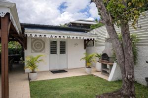 a house with a white door and a tree at Le cocon de Josie avec Jacuzzi & Piscine Privée, Le Lamentin, Martinique in Le Lamentin +21 photos