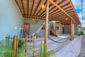 a porch with a hammock under a wooden pergola at Casas Costa Dos Corais - 200m do mar, Climatizada, Confortável e Completa in Japaratinga