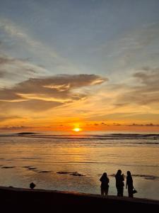 a group of people standing on the beach watching the sunset at Loko Stay Syariah in Krui