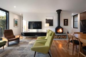 a living room with a fireplace and a green chair at Banjo Treehouse in Hepburn Springs