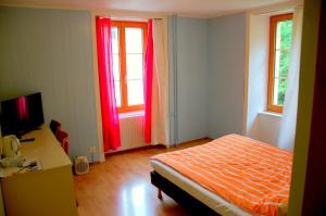 - une chambre avec des rideaux rouges, un lit et un bureau dans l'établissement Hôtel de l'ours, à Vuiteboeuf