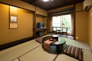 a living room with a table and a television at Ichirino Kogen Hotel Roan in Hakusan