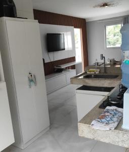a kitchen with white cabinets and a tv on the wall at DR Rbs in Ponta Grossa