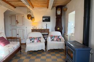 a room with two chairs and a table and a clock at Le Clos Lau-Tave Charming 110 m Provençal home with private garden in Simiane-la-Rotonde