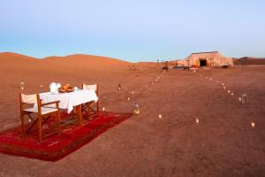 a table in the middle of a desert with candles at Luxury Camp By DAR AZAWAD in Mhamid