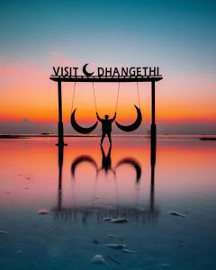 a man on a swing on the beach at sunset at Diamond Stay Inn in Dhangethi