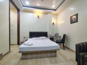 a bedroom with a bed and a chair and a desk at Hotel Holiday Palace in Sibsāgar