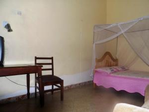 een slaapkamer met een bed, een stoel en een bureau bij Vine Inn in Mbarara