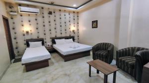 a hotel room with two beds and two chairs at Hotel Holiday Palace in Sibsāgar