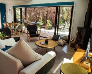 a living room with a couch and a table and chairs at Tongariro Suites in Ohakune