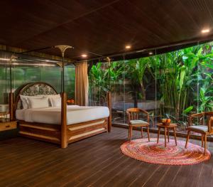 a bedroom with a bed and two chairs and a table at Eleve in Assagao