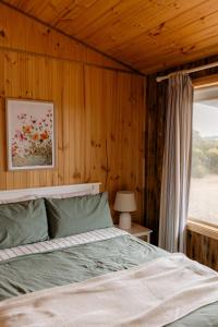 a bedroom with wooden walls and a bed with a window at Sampsons Shack in Vivonne Bay