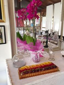 una mesa con un pastel y un jarrón de flores en Casa Fogli Casa Vacance & Events, en Campiglia Marittima