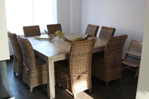 a dining room table with wicker chairs and a wooden table at La Crème in Ostend