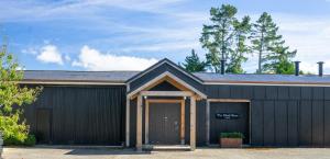 a black building with two garage doors and trees at The Black Barn At Puketitiri in Puketitiri