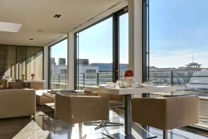 a dining room with tables and chairs and large windows at The Mandala Suites in Berlin