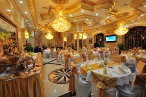 un salón de banquetes con mesas y sillas blancas y lámparas de araña en Hotel Arca lui Noe, en Sinaia