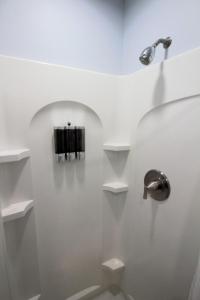 a bathroom with white walls and a toilet with shelves at The Hut at Deer Hollow in Three Rivers