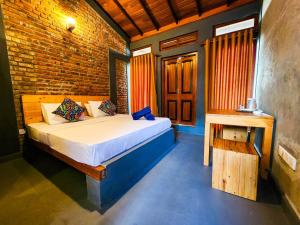 a bedroom with a bed and a brick wall at Pearl Bolgoda in Piliyandala