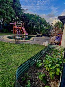 a garden with a playground in the background at Backpacker Bunks and Queen Pool Clifton Beach in Clifton Beach