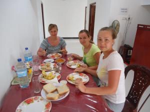 three girls sitting at a table eating food at Blue Moon Rest Inn in Trincomalee
