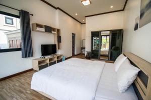 a bedroom with a large white bed and a television at laboon pool villa Pranburi in Ban Nong Ban Kao