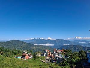 a village on a hill with mountains in the background at Mountain View Homestay in Tānsen