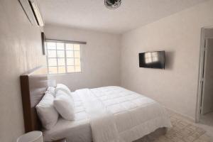 a bedroom with a white bed and a television at Private Apartment in Prague Poniente Area in Hermosillo