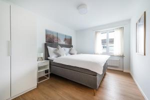 a white bedroom with a large bed and a window at COZY 1 !Gratis Parken, Free Parking! in Weinfelden +3 photos