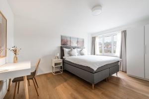 a white bedroom with a bed and a desk at COZY 1 !Gratis Parken, Free Parking! in Weinfelden