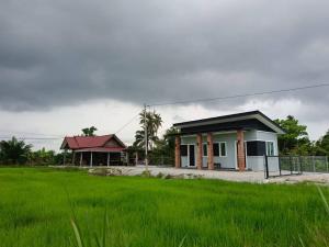 a small house with a green field in front of it at All Rushd Private Pool Homestay in Sungai Besar