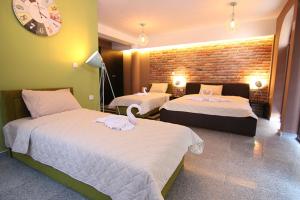 ein Hotelzimmer mit zwei Betten und einer Uhr an der Wand in der Unterkunft Hotel Korzo in Bitola