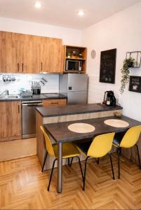 a kitchen with a table and yellow chairs at Krstić_lux apartman in Subotica
