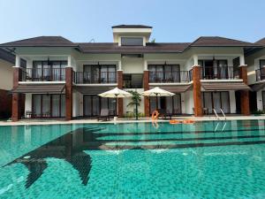 a person in a swimming pool in front of a building at KTDC Malabar Courtyard in Mulappilangād