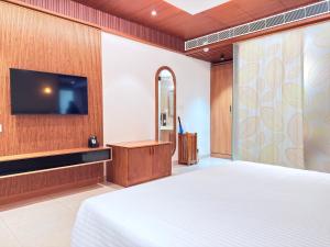 a bedroom with a bed and a flat screen tv at KTDC Malabar Courtyard in Mulappilangād