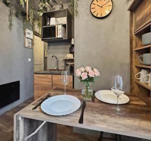 a table with plates and glasses and a clock on the wall at Petit nid douillet, à deux pas des commodités in Neuilly-Plaisance +26 photos